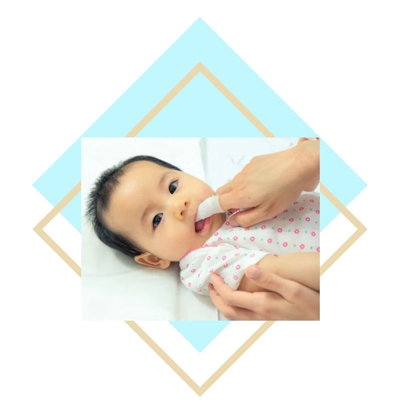 Baby having gentle dental care with a soft cloth on gums for oral hygiene.