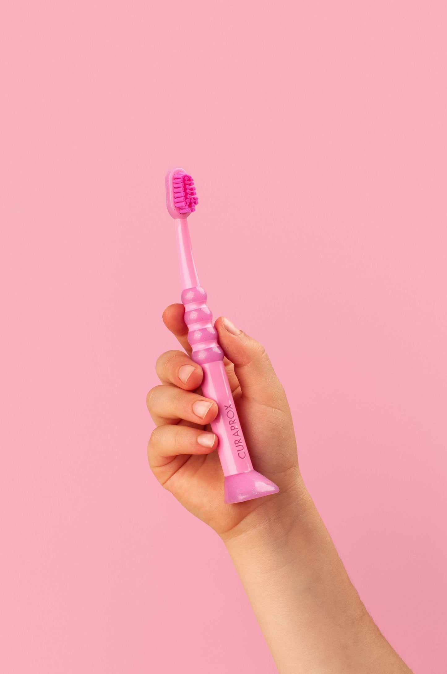 Pink Curaprox Baby Toothbrush for ages 0-4 with fine, dense Curen® filaments and ergonomic anti-slip handle.