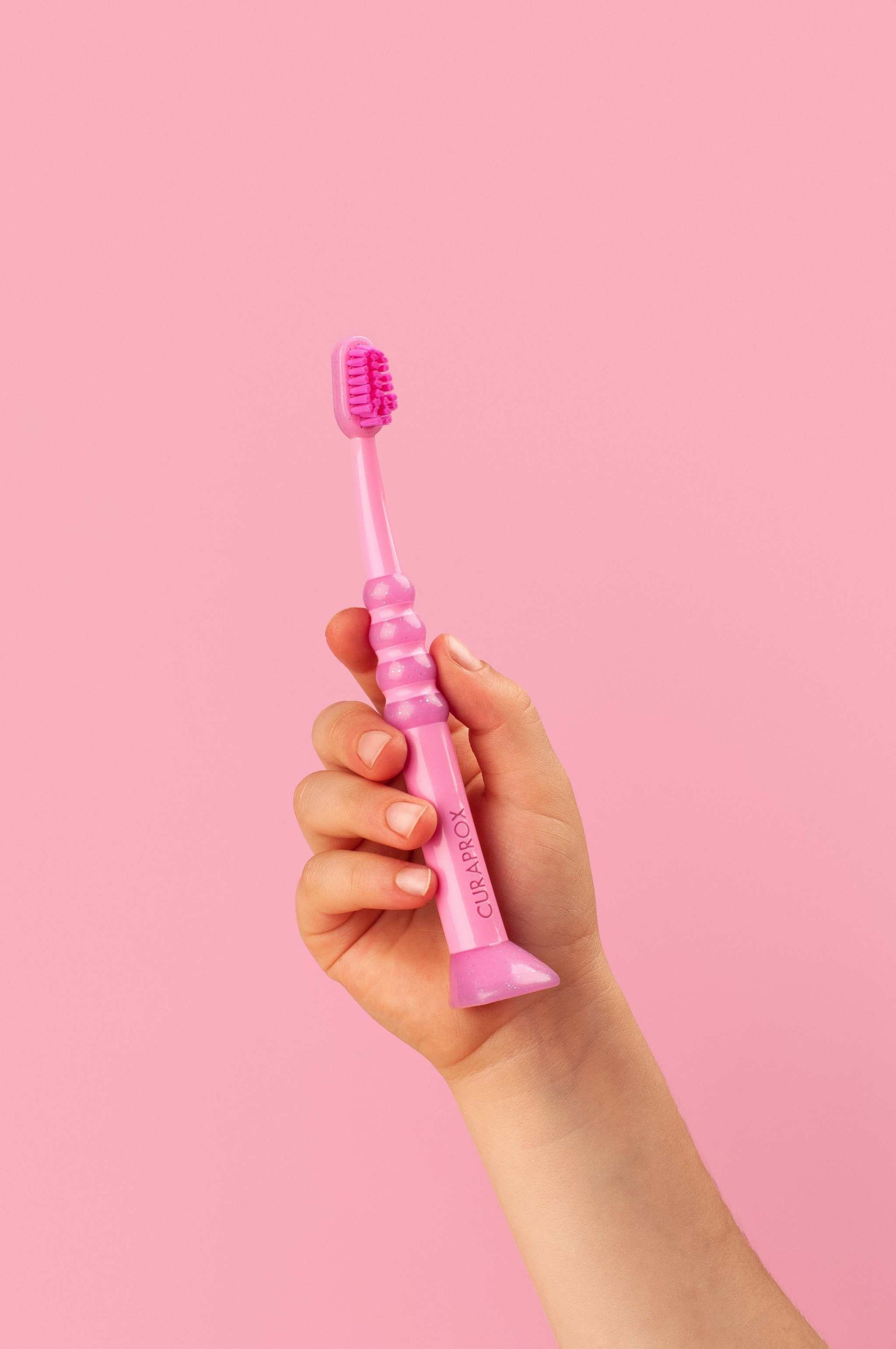 Pink Curaprox Baby Toothbrush for ages 0-4 with fine, dense Curen® filaments and ergonomic anti-slip handle.