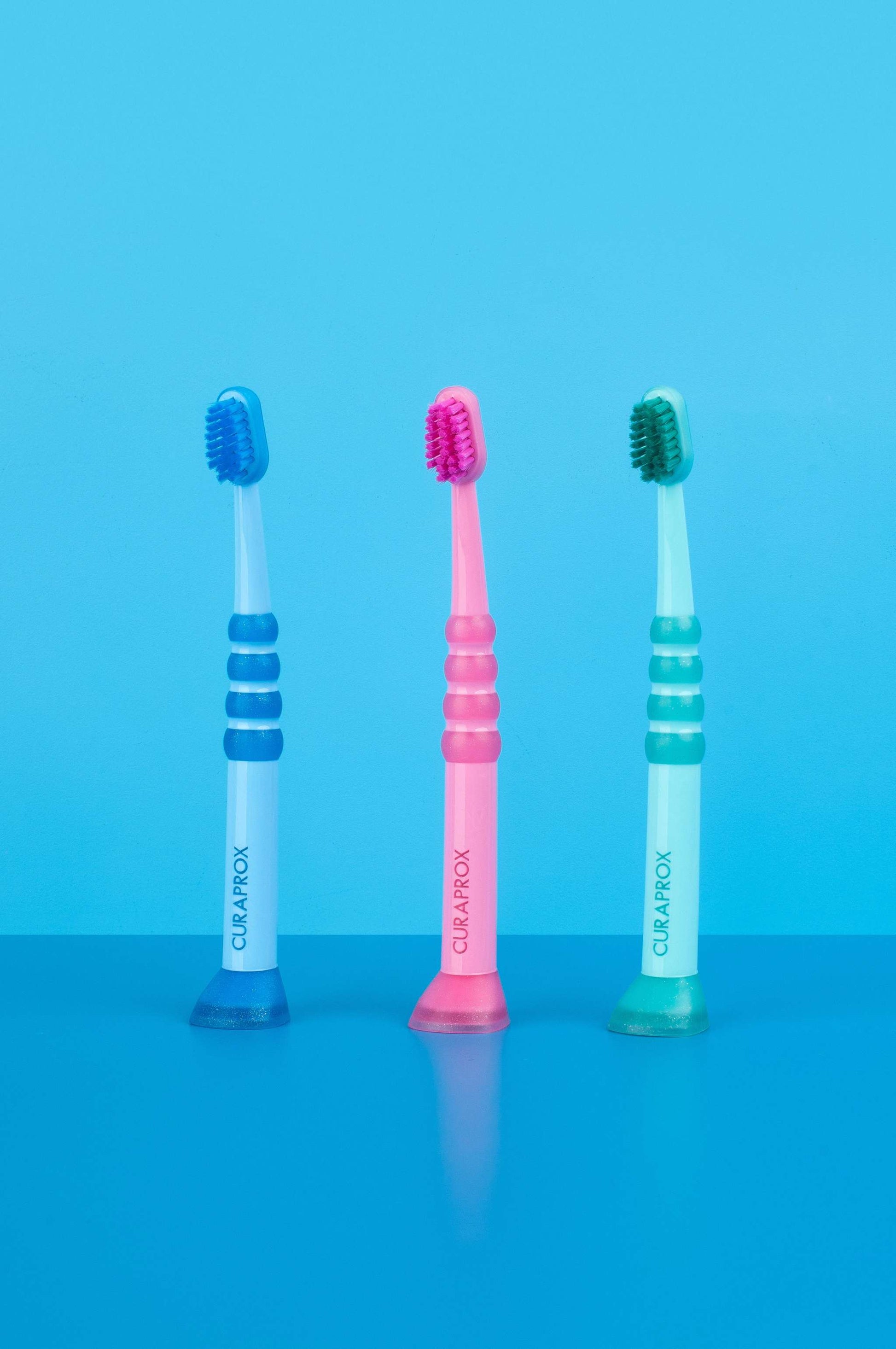 Curaprox Baby Toothbrushes for 0-4 years with fine, dense Curen filaments and rubberized heads in blue, pink, and green colors.