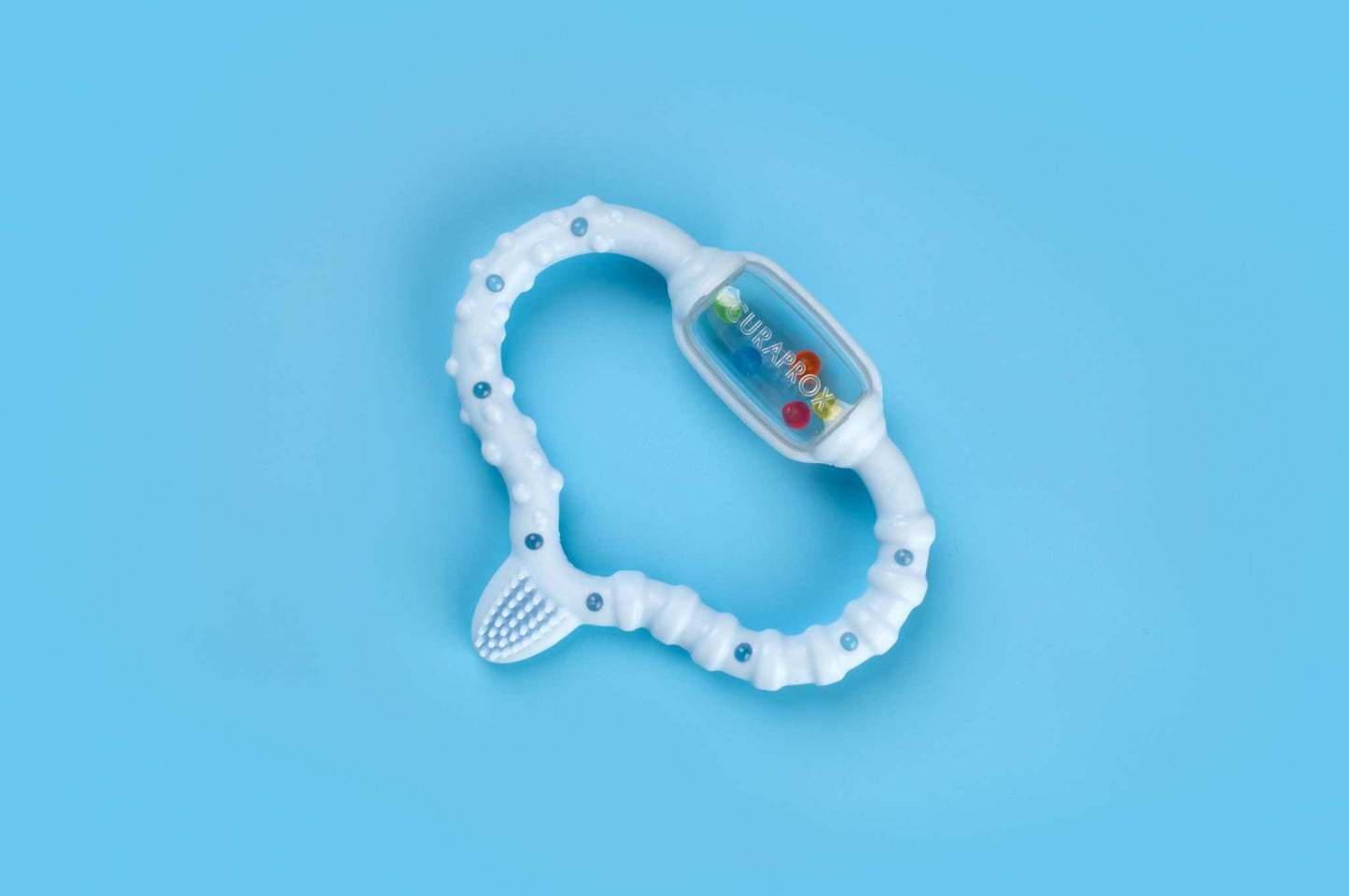 Curaprox Baby teething ring with textured surface and colorful beads on blue background