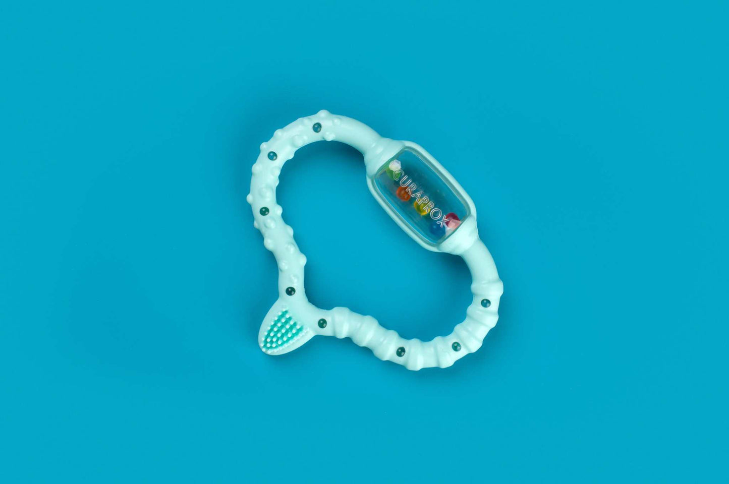 Curaprox Baby teething ring with textured handle and clear rattle on blue background