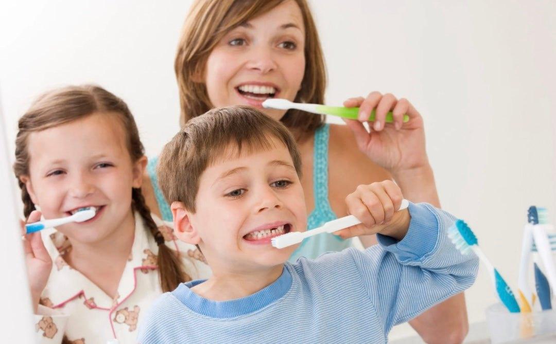 Mother and children brushing teeth together, promoting fun winter brushing routines for kids