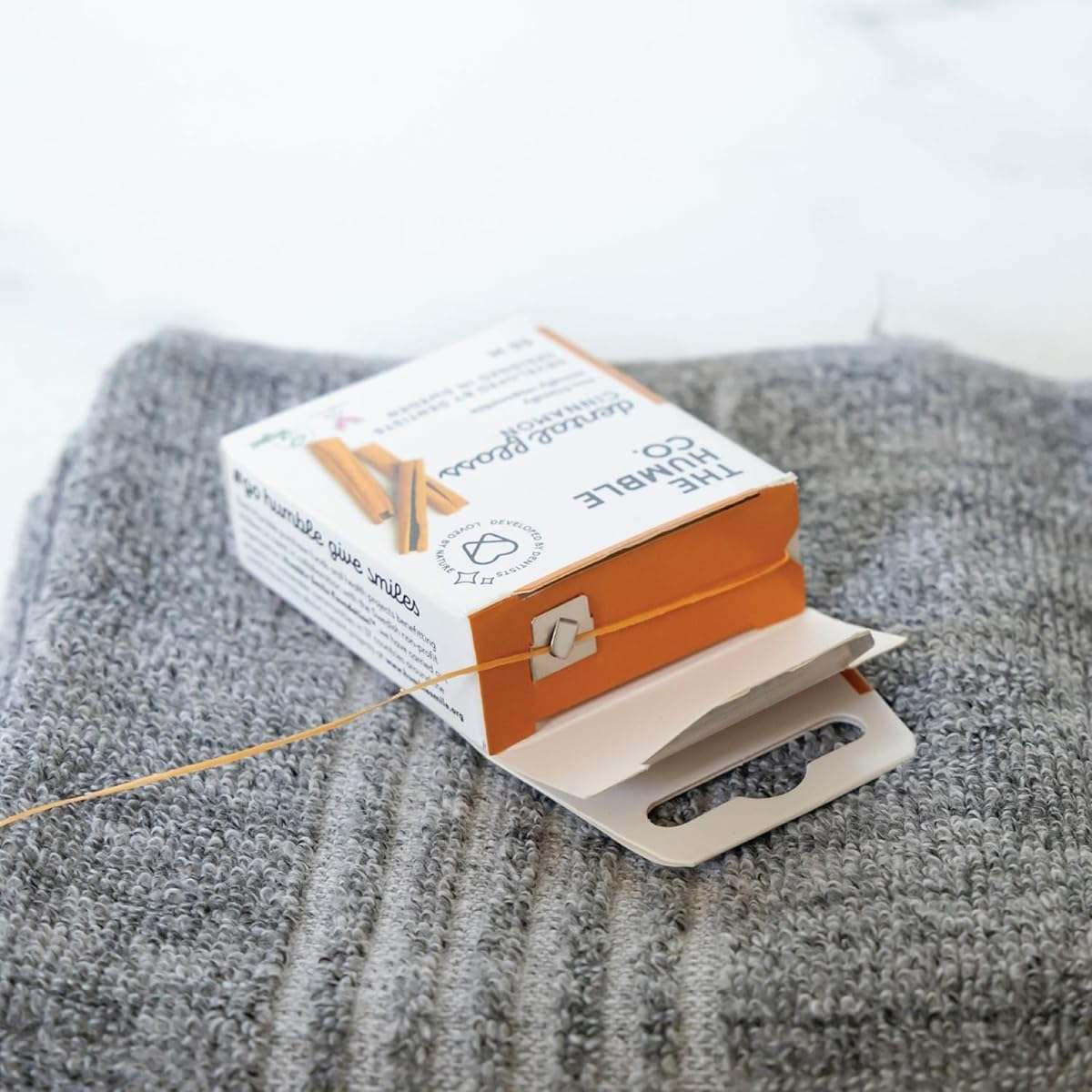 Humble Natural Dental Floss eco-friendly recyclable packaging with 50 meters of durable floss on gray towel