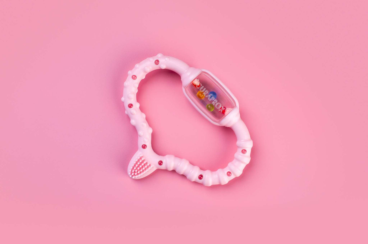 Curaprox Baby pink textured teething ring on pink background