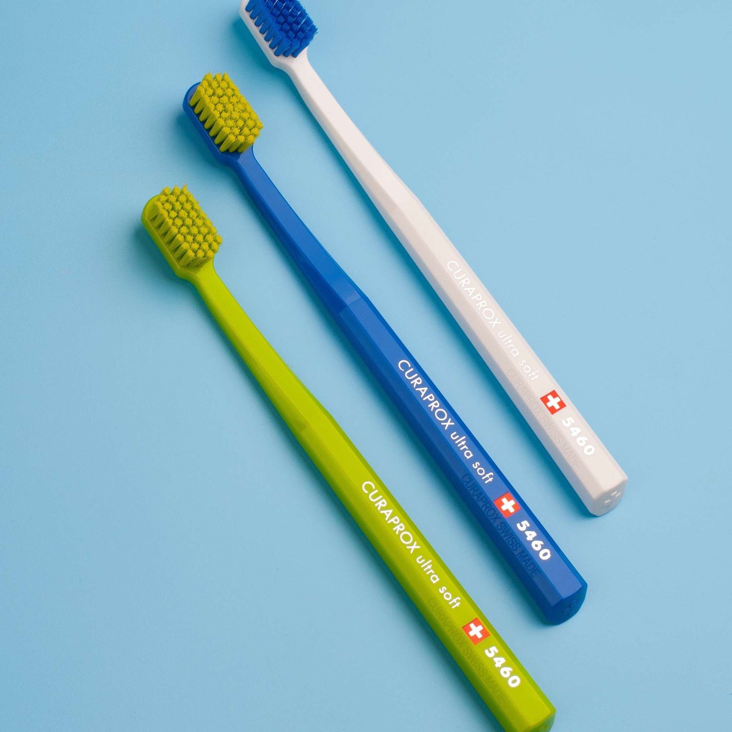 Curaprox CS 5460 ultra soft toothbrushes in white, blue, and green with densely packed bristles and octagonal handles for gentle effective cleaning.