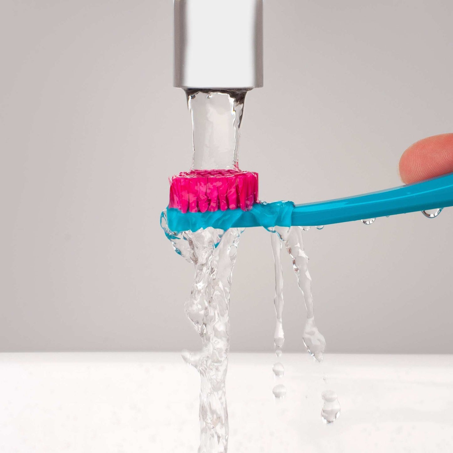Curaprox CS 5460 ultra soft toothbrush with blue handle and pink bristles under running water