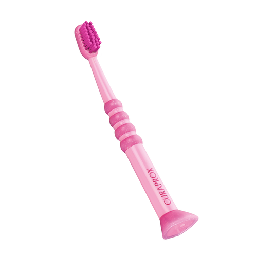 Curaprox Baby Toothbrush in pink with soft, densely packed filaments and rubberized small head for gentle cleaning of infant teeth.